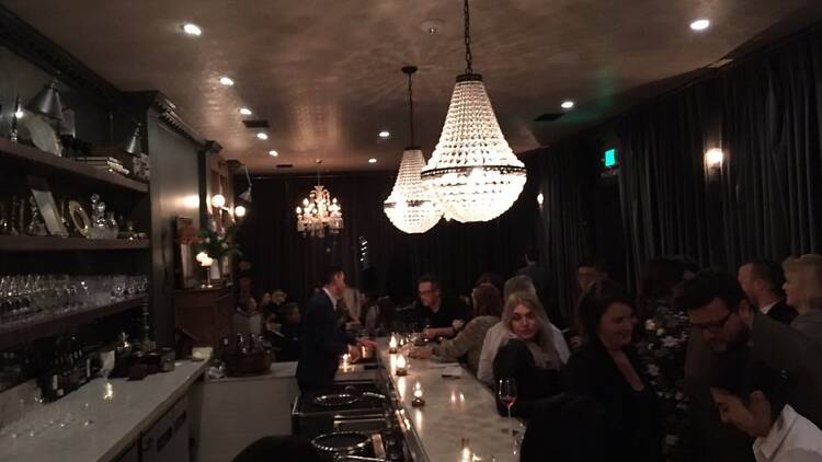 Chandeliers hanging over the white bar at Bar Crenn