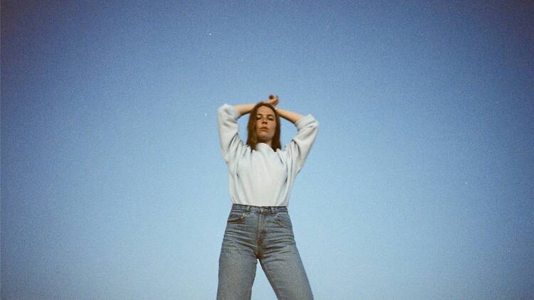 Maggie Rogers standing on a blue background.