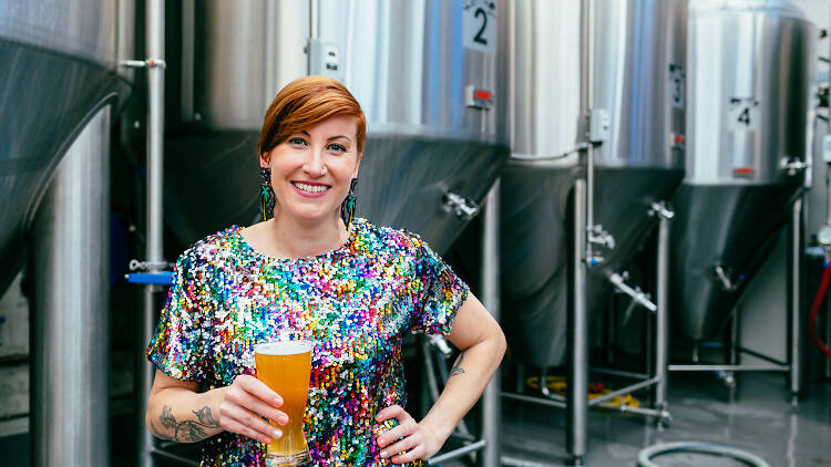 Woman in a sparkly rainbow shirt holding a beer