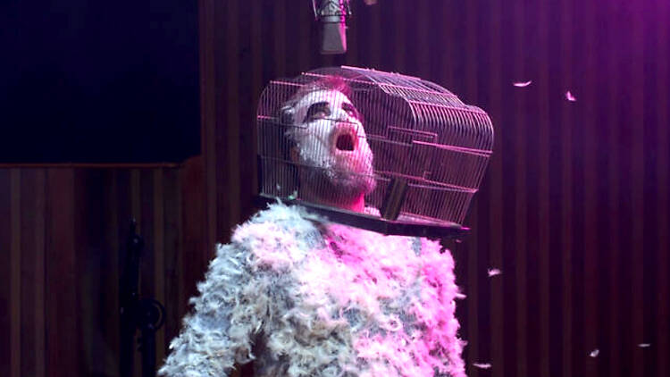 Person with gage on head, covered in feathers, John Grant, 'Love Is Magic' 2018 album cover