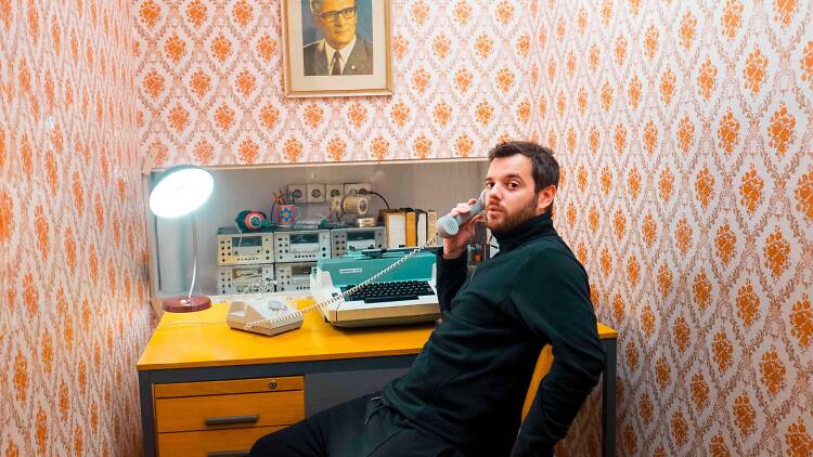 Mike Skinner sat at a desk holding a phone to his ear