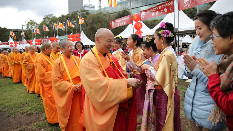 People standing in a line shaking hands with Buddhist monks.