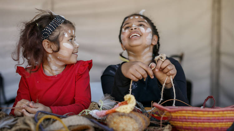 Two kids in Indigenous face paint doing craft.