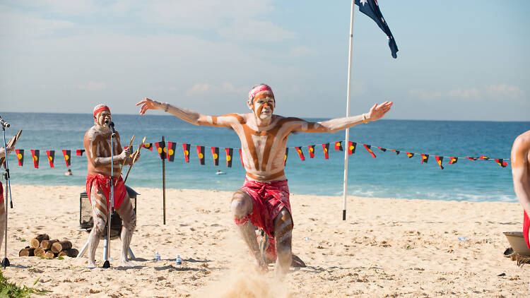 Indigenous dancers in a performance on the beach.
