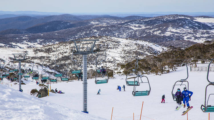 People enjoying a day of skiing and snowboarding at Blue Cow ski resort in Perisher.