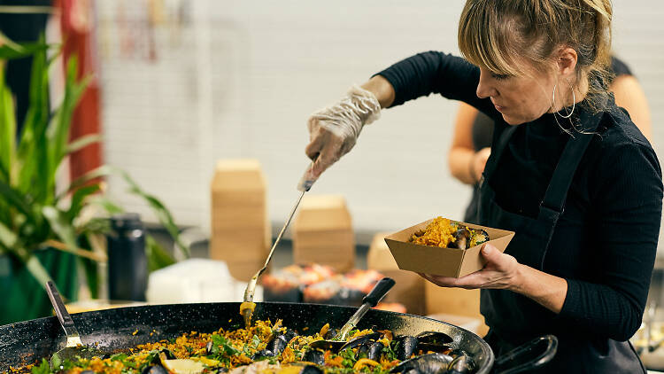 Woman dishing up bowl of paella