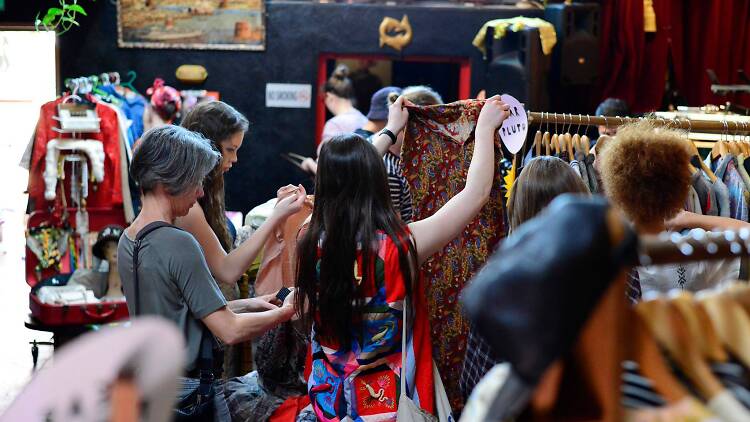 People shopping at a colourful clothing market.