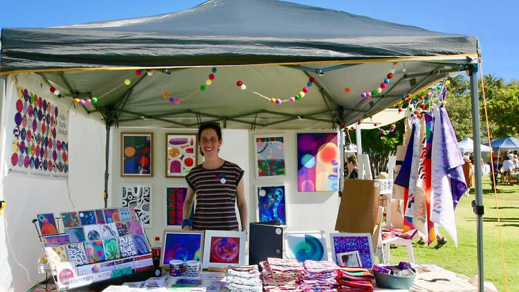 Woman stallholder standing behind her textile offerings.