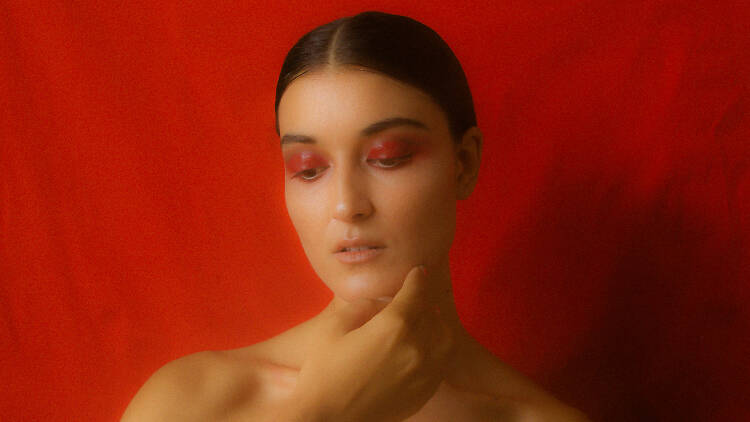 Singer-songwriter Milan Ring poses in front of a red backdrop.