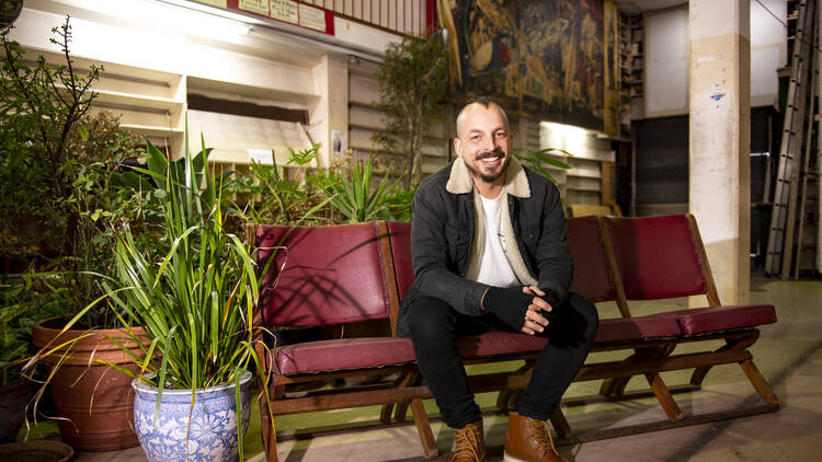 Commune founder Sam Ali sitting at the Newtown venue, smiling and sitting on cinema-style chairs