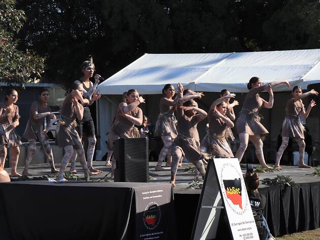 AbSec’s NAIDOC Family Fun Day Young Indigenous dancers in traditional dress from Redfern Dance Company dance on stage.