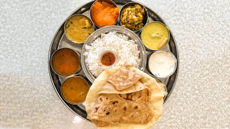 A thali plate with curries, rice and naan