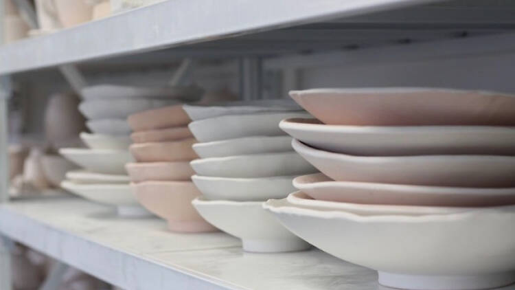 Different coloured ceramic bowls and plates on a shelf