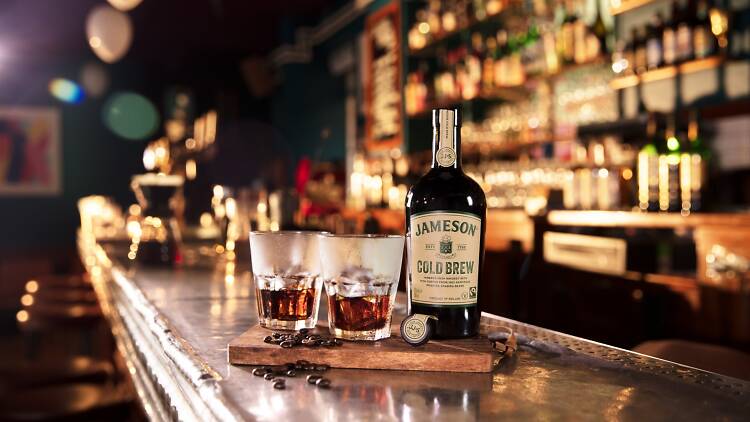 Two cups and a bottle of Jameson Cold Brew on a bar.