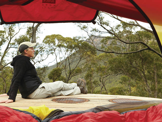 Camping in the Grampians Person sitting outside a tent with bushland in the background