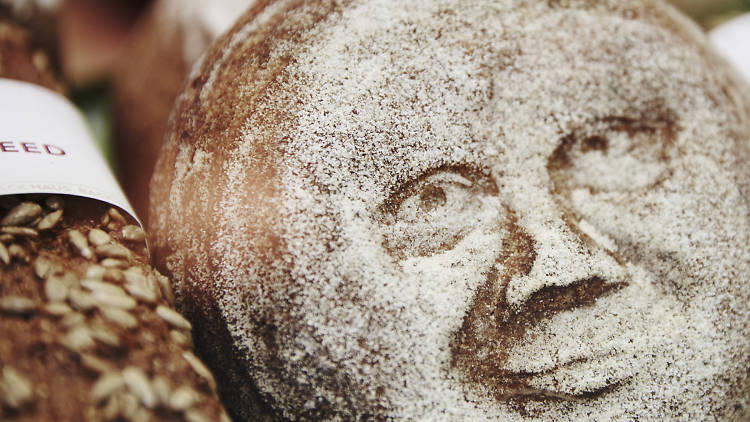 A loaf of bread with a spookily realistic flour face on it