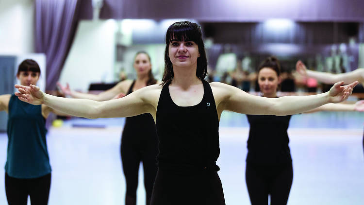 Woman in black leotard leading ballet class