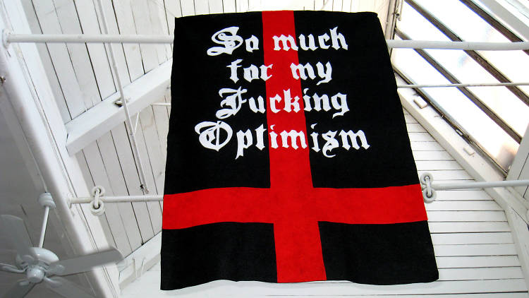 A black flag with a red cross on it overlaid with "So much for my Fucking Optimism" in white gothic font
