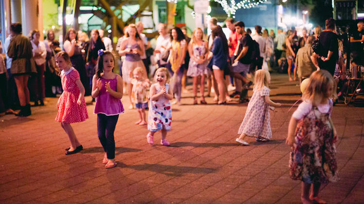 Kids and families dancing under fairy lights.