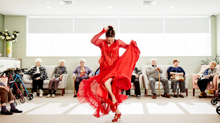 Woman in a red dress dancing in front of seated elderly people for Blacktown's Magnify festival.