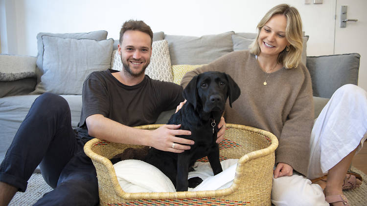 Couple sits in their living room with Guide Dog puppy, Mac.