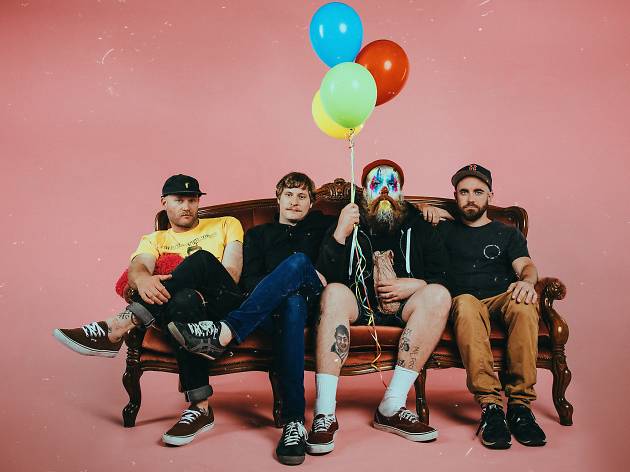 Totally Unicorn Wollongong band Totally Unicorn sitting on a lounge with balloons and a pink background.