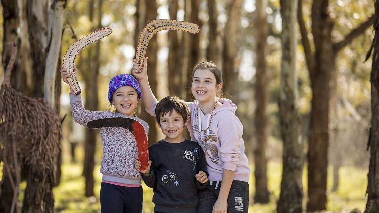 Kids with boomerangs in the bush at Rouse Hill House and Farm.