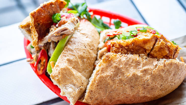 Banh mi cut in half with pork crackling in a red basket