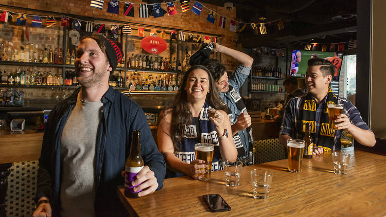 People wearing footy colours cheering in pub