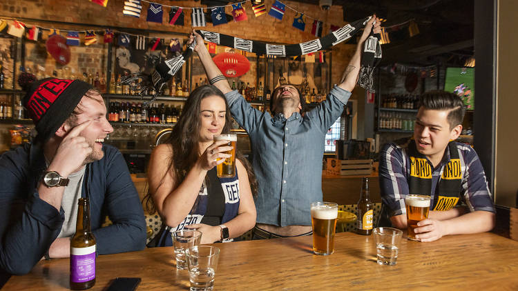 People wearing footy colours drinking in pub