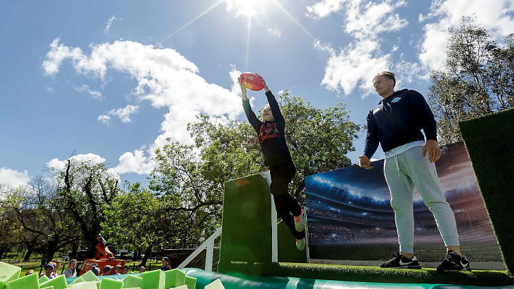 Kid marking a ball over a foam pit at the 2016 AFL Footy Festival