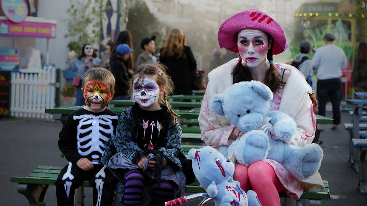 Two children and a woman dressed in Halloween costumes