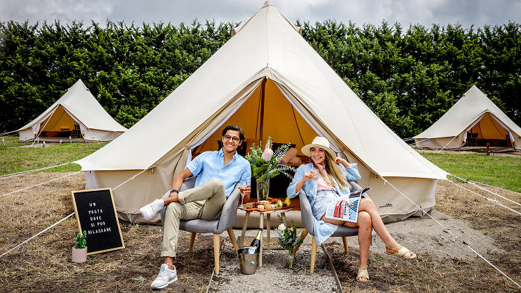 Couple relax in front of glamping tent