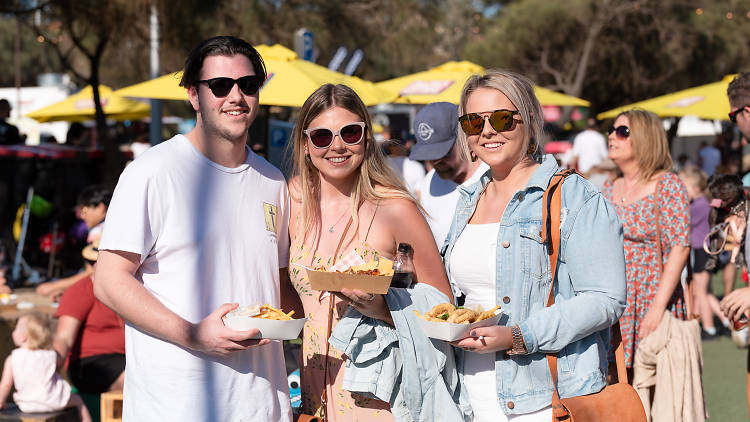 Three people smile at festival