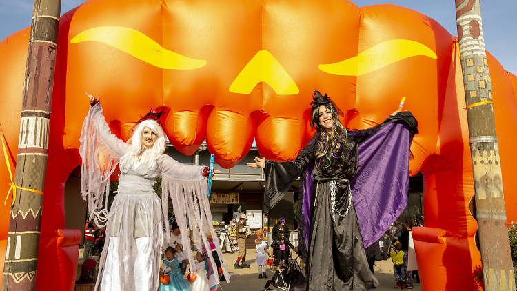 Two people in Halloween costumes in front of an inflatable pumpkin