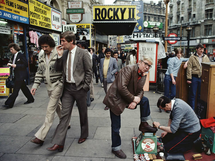 ‘Shoes polisher, Rocky II, etc, Piccadilly’ by William Klein (1980