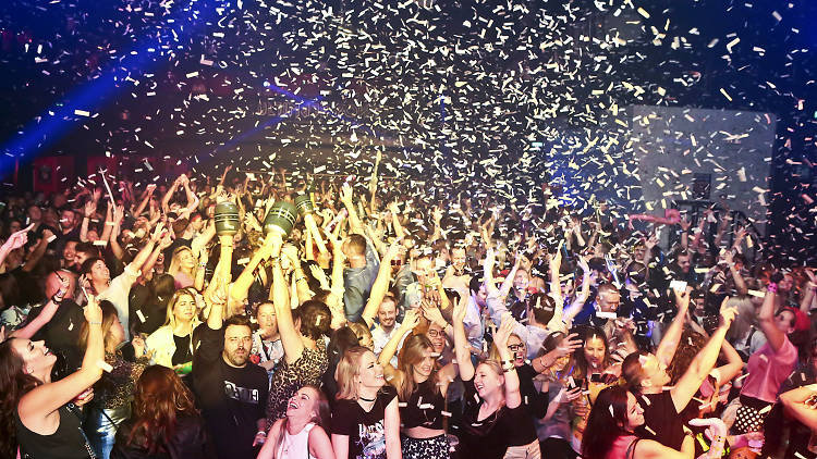 People dancing in a nightclub with confetti falling.