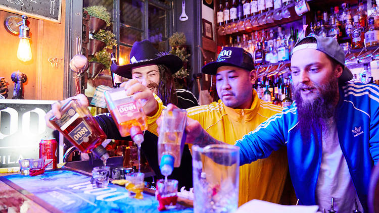 People pouring drinks at a bar.