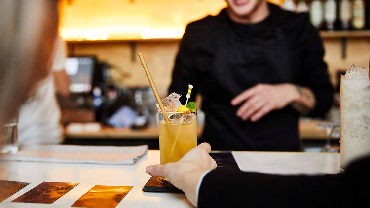 A person at a bar buying a cocktail.