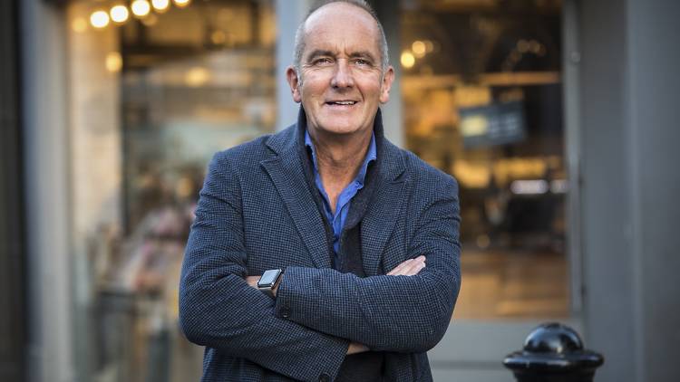 Grand Designs host Kevin McCloud stands wearing a jacket.