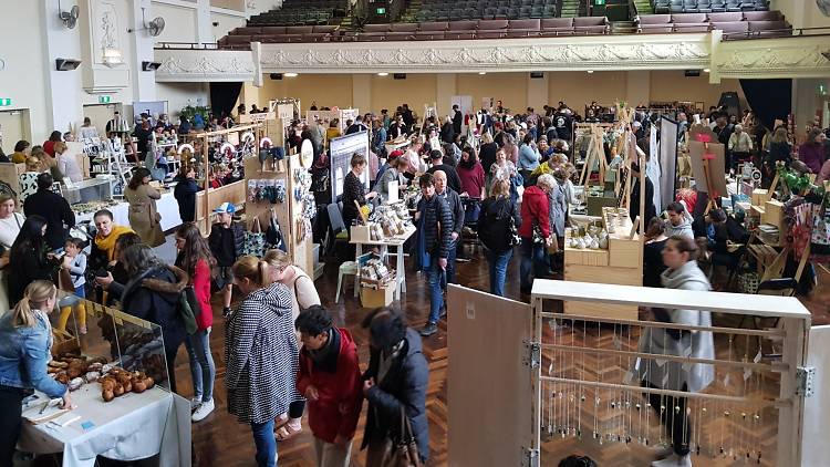 A hall is filled with market stalls and browsing shoppers