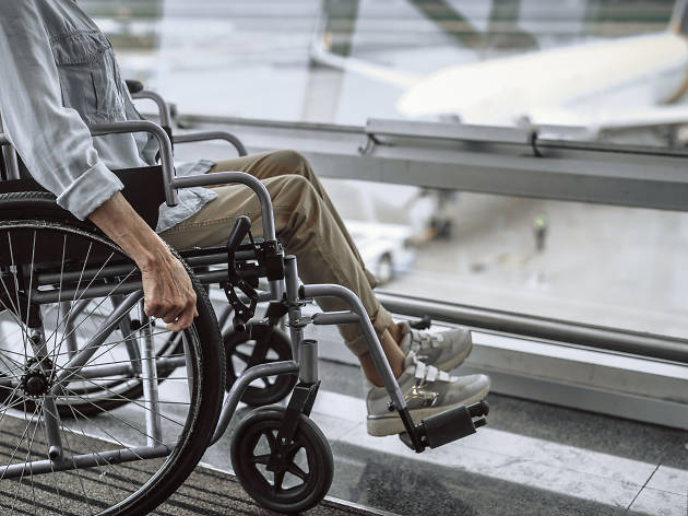 Old woman on wheelchair near window in airport Old woman on wheelchair near window in airport