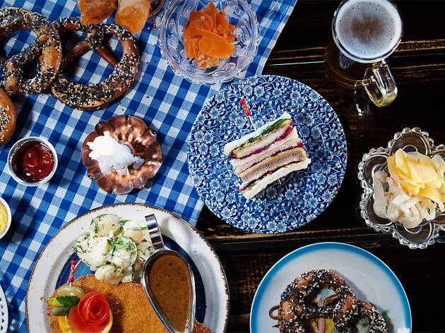 Cuckoo A gingham covered table topped with pretzels, beers, schnitzels and sandwiches