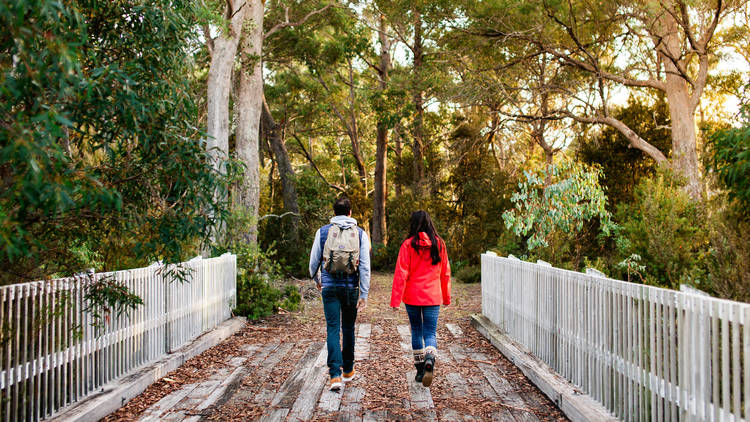 Two people walking over a bridge near Pumphouse Point