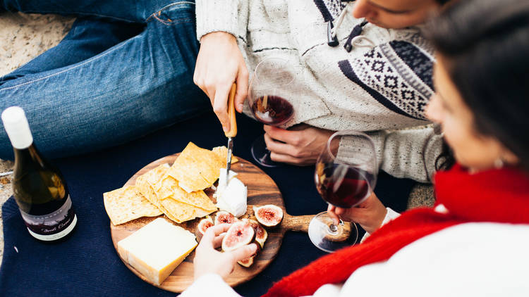 Close up of people eating cheese and wine