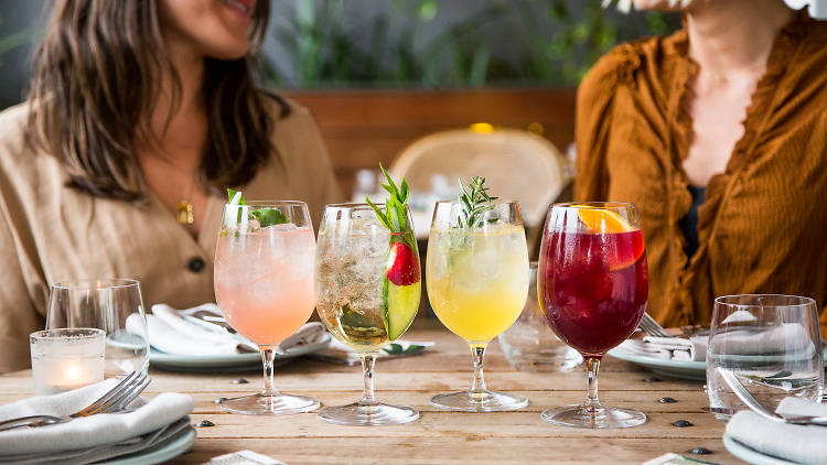 People sitting at a table with colourful cocktails.