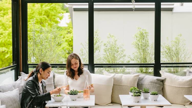 Two girls eating lunch in the courtyard at Daily Greens