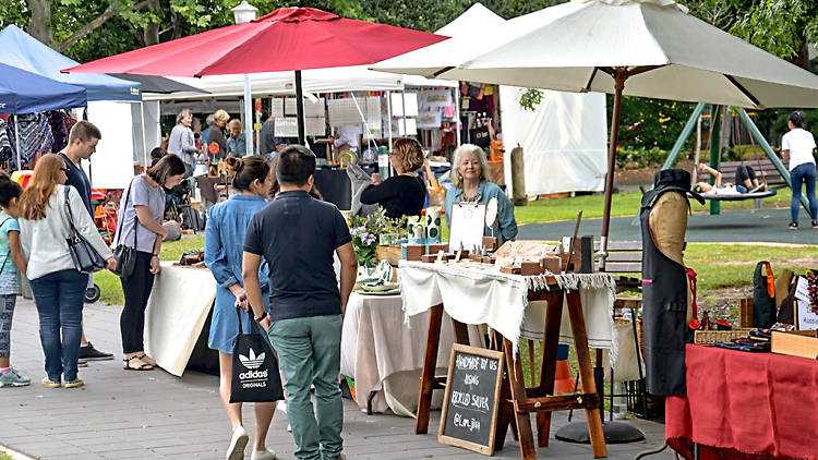 People browse outdoor market stalls.