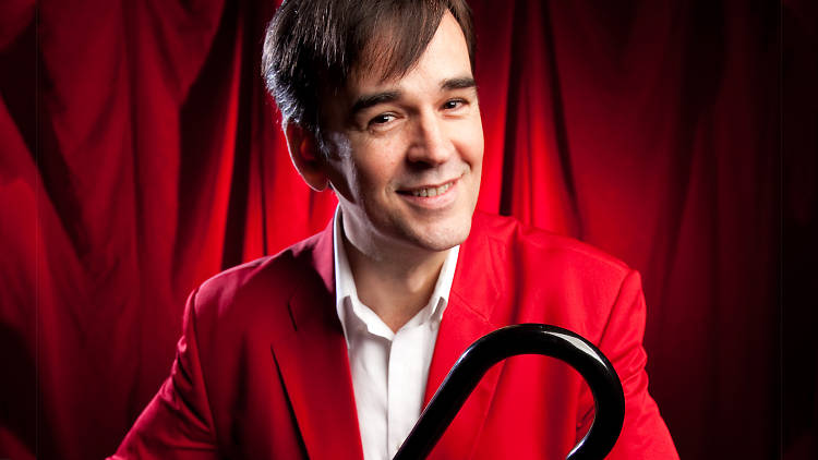 Press shot of comedian Tim Ferguson in a red suit and cane