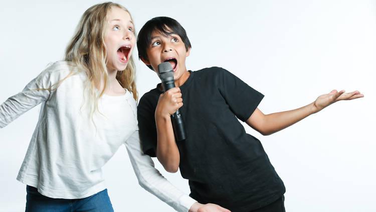 Kids singing into a microphone.
